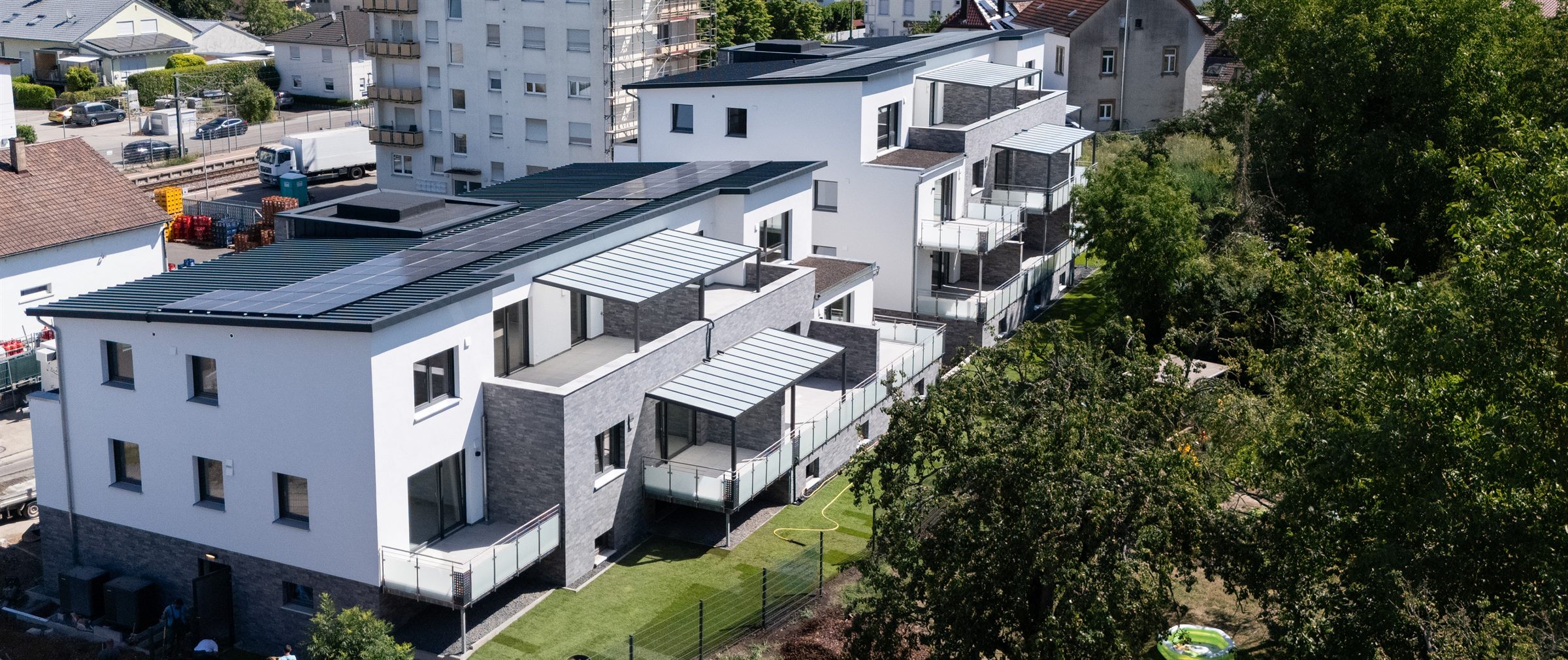 Luftaufnahme des Neubaus in Kraichtal-Unteröwisheim mit Balkonen, Terrassen und Photovoltaik auf den Dächern